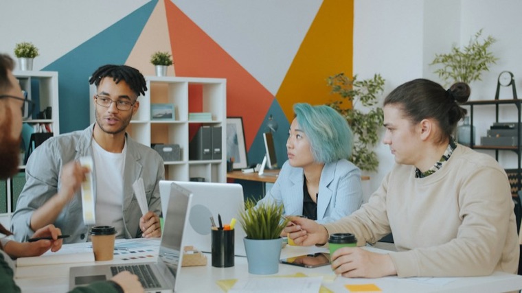 Design team collaborating around a table in a colourful studio